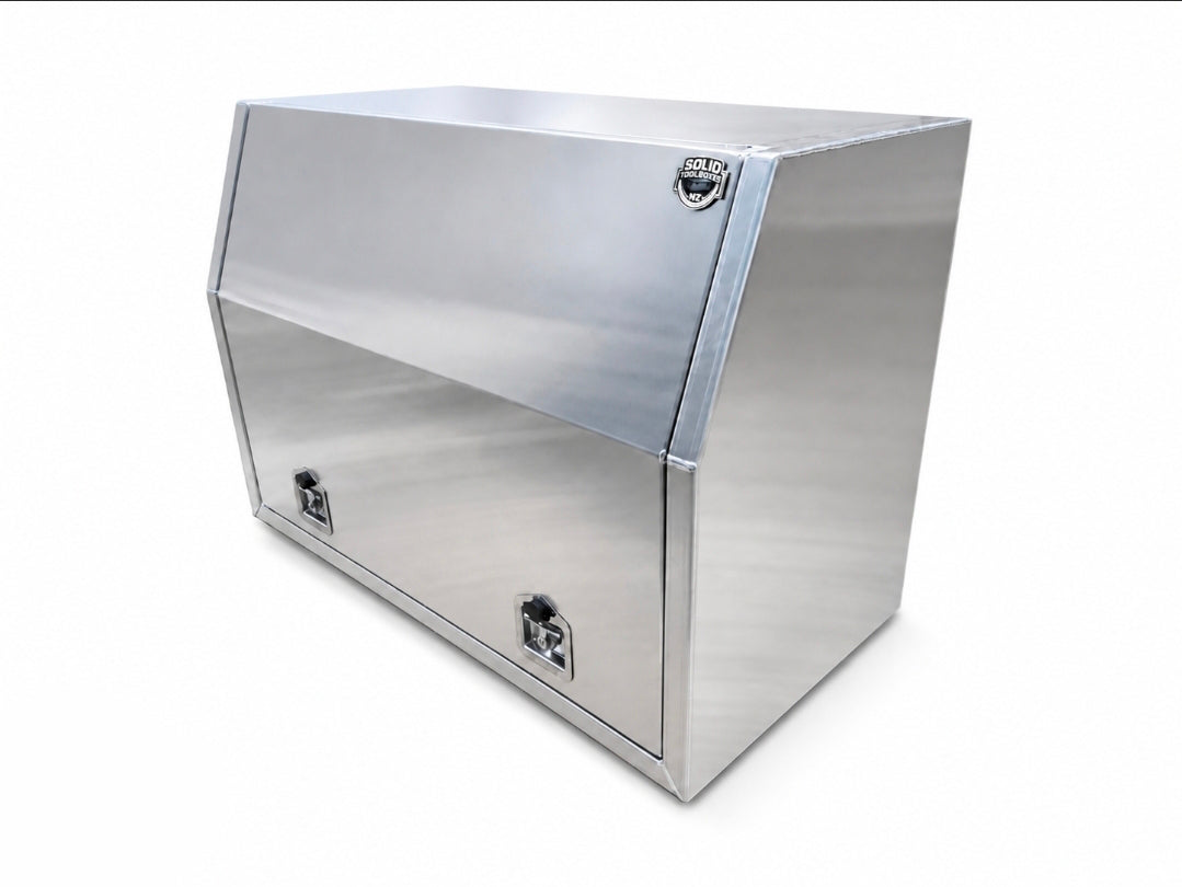 A aluminum toolbox with a hinged upper door, two lockable lower compartments, and a small circular badge on the top right, shown on a plain white background.