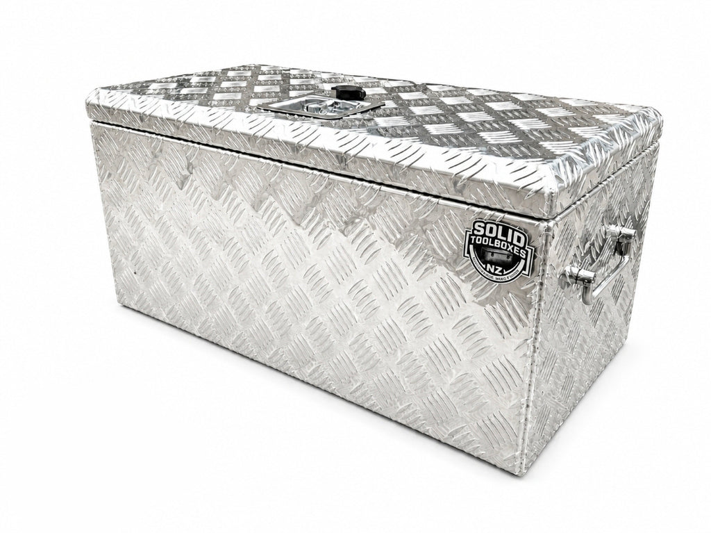 A rectangular aluminum toolbox with a diamond plate pattern, featuring a lid with a latch and handle, set against a plain white background.