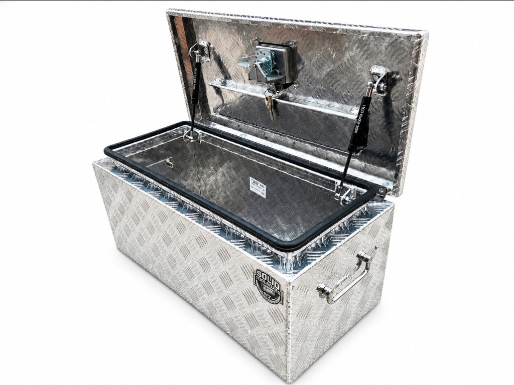 An open diamond-plate aluminum toolbox with a black-trimmed interior and a lockable lid, shown on a plain white background.