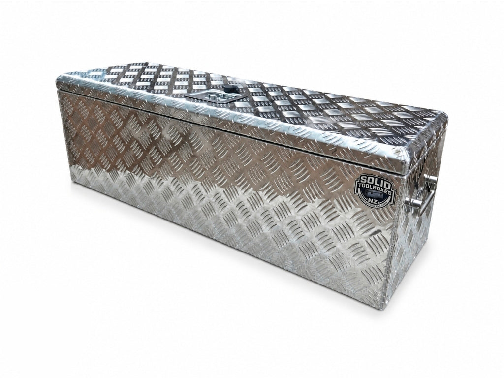 A rectangular aluminum toolbox with a diamond plate pattern, featuring a lid, side handles, set against a plain white background.