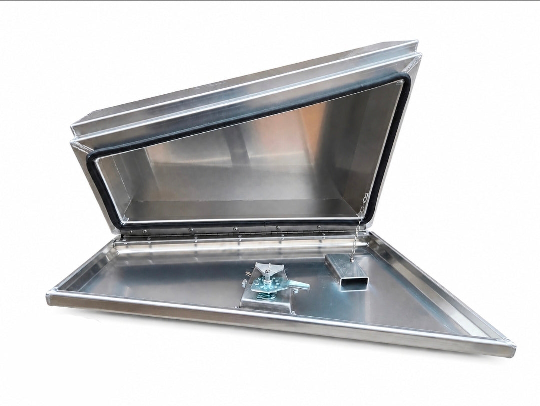 An aluminium toolbox with its lid open, showing the interior and a small metal cap or plug on the tray, photographed against a plain white background.