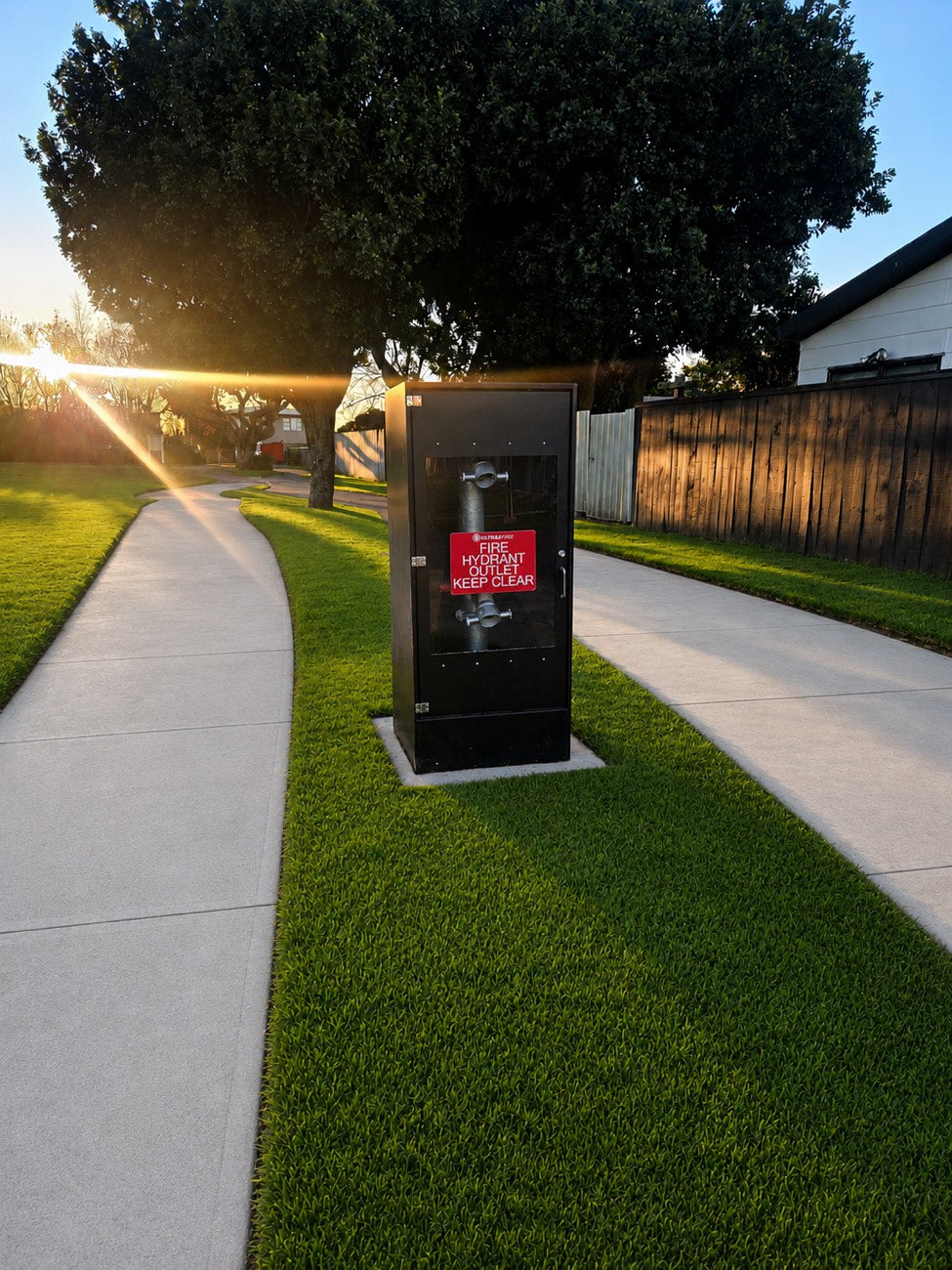 Black riser cabinet on a residential berm at dusk